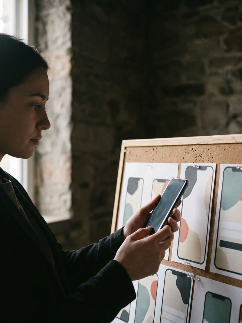 Designer a comparar um protótipo no telemóvel com ecrãs da app impressos